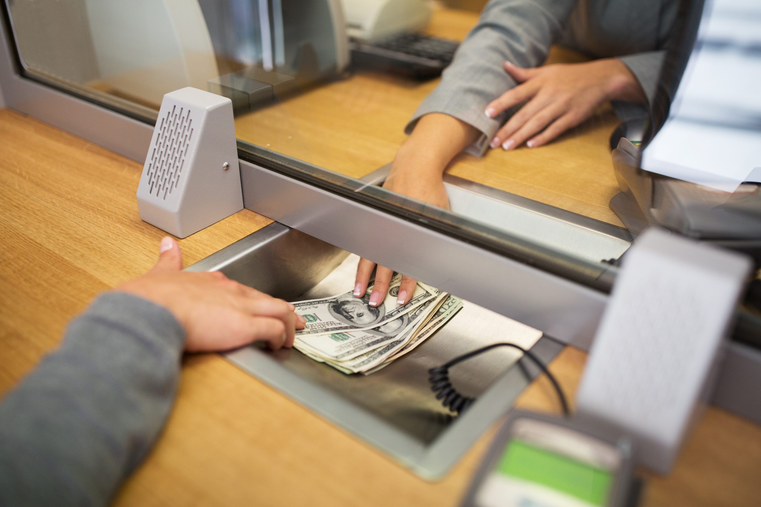 people, withdrawal, saving and finance concept - clerk giving cash money to customer at bank office or currency exchanger